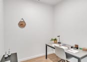 Thumbnail 18 of 50 - A white desk with a plant and a clock on the wall.