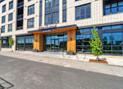 Thumbnail 41 of 50 - A modern building with a glass entrance and a wooden overhang.