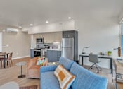 Thumbnail 9 of 50 - A modern living room with a blue couch and a kitchen in the background.