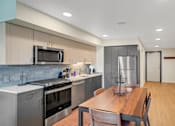 Thumbnail 8 of 50 - A modern kitchen with a wooden table and chairs.