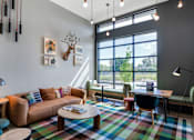 Thumbnail 39 of 50 - A modern living room with a large window and a colorful rug.