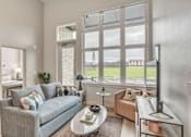 Thumbnail 7 of 50 - A living room with a grey couch and a large window.