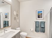 Thumbnail 27 of 50 - A bathroom with a white sink, toilet, and a grey shower curtain.