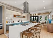 Thumbnail 33 of 48 - A modern kitchen with a long white island and wooden chairs.