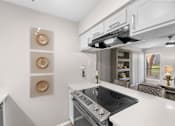 Thumbnail 3 of 26 - A modern kitchen with a stove top oven and a range hood.