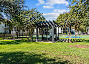 Thumbnail 21 of 26 - A pavilion with a black and white checkered roof is surrounded by trees.
