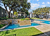 Thumbnail 18 of 26 - A swimming pool surrounded by a stone wall and a grassy area.