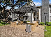 Thumbnail 24 of 26 - A patio with a stone wall and a metal grill.