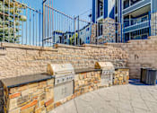 Thumbnail 27 of 33 - A stone wall with a built-in grill and a metal fence.