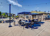 Thumbnail 24 of 33 - A patio with tables and chairs under string lights.