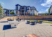 Thumbnail 30 of 33 - A playground with a ping pong table and benches is surrounded by a brick wall and apartment buildings.
