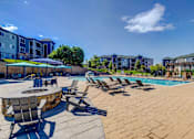 Thumbnail 25 of 33 - A poolside area with chairs and a table.
