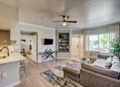 Thumbnail 5 of 33 - A modern living room with a brown couch and a white kitchen area.