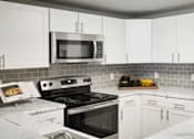 Thumbnail 6 of 33 - A kitchen with white cabinets and a black stove top oven.