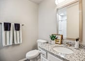 Thumbnail 12 of 48 - A bathroom with a toilet, sink, mirror, and towel rack.