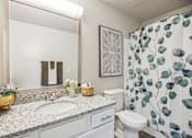 Thumbnail 11 of 48 - A bathroom with a sink, toilet, and a shower curtain with leaf patterns.