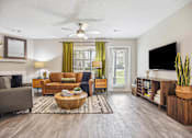 Thumbnail 7 of 48 - A living room with a grey couch, a brown sofa, a wooden coffee table, a flat screen TV, and a ceiling fan.