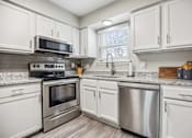 Thumbnail 3 of 48 - A kitchen with white cabinets and stainless steel appliances.