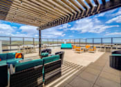 Thumbnail 21 of 28 - A patio with a wooden roof and several chairs and tables.