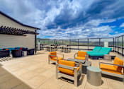 Thumbnail 22 of 28 - A patio with orange chairs and a table.