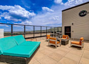 Thumbnail 23 of 28 - A patio with a couch, chairs, and a table with a view of the sky.