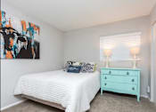 Thumbnail 13 of 20 - A bedroom with a white bed and a blue dresser.