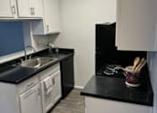 Thumbnail 14 of 20 - A kitchen with black countertops and white cabinets.