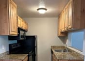 Thumbnail 16 of 20 - A kitchen with black appliances and wooden cabinets.