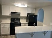 Thumbnail 17 of 20 - A kitchen with black appliances and white cabinets.