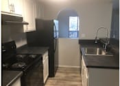 Thumbnail 18 of 20 - A kitchen with black countertops and white cabinets.