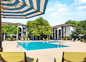 Thumbnail 3 of 20 - A pool surrounded by yellow chairs and umbrellas.