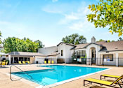 Thumbnail 4 of 20 - A pool with a yellow bench and a building in the background.