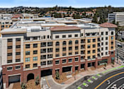 Thumbnail 29 of 29 - A large building with a red roof and a parking lot in front.