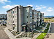 Thumbnail 30 of 30 - A modern apartment building with a parking lot in front.