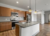 Thumbnail 6 of 30 - A kitchen with a white island and wooden cabinets.