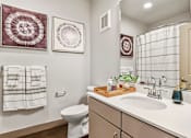 Thumbnail 11 of 30 - A bathroom with a white toilet, a sink, and two wall hangings.