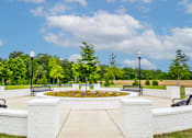 Thumbnail 13 of 26 - A park with a white brick wall and benches.