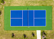Thumbnail 14 of 26 - A tennis court surrounded by grass and trees.