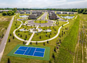 Thumbnail 15 of 26 - A tennis court is surrounded by a green lawn and a pond.