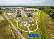 Thumbnail 16 of 26 - A large, well-maintained outdoor recreational area with a playground, tennis courts, and a pond.