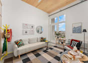 Thumbnail 2 of 12 - A living room with a white couch and a checkered floor.