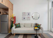 Thumbnail 7 of 12 - A living room with a couch, a mirror, and pictures on the wall.