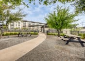 Thumbnail 20 of 26 - a park with picnic tables and trees in front of a building