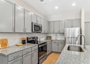 Thumbnail 1 of 34 - A kitchen with grey cabinets and a granite countertop.
