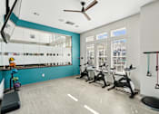 Thumbnail 14 of 29 - A gym with a mirror, exercise equipment, and a fan.