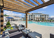 Thumbnail 22 of 29 - A pool area with a wooden pergola and lounge chairs.