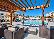 Thumbnail 21 of 29 - A pool area with a wooden pergola and wicker chairs.