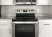 Thumbnail 19 of 27 - Renovated Kitchen with white cabinets and stainless steel stove/oven and microwave