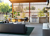 Thumbnail 21 of 34 - A patio with a grey couch, a table and chairs, and a fireplace.