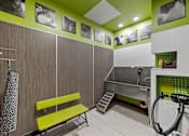 Thumbnail 16 of 28 - A room with a green bench and pictures on the wall.